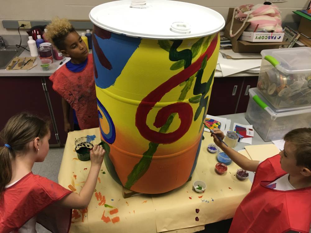 Students painting a rain barrel